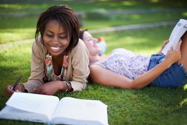 Studiare l'università e gli studenti sull'erba con libri per l'apprendimento delle conoscenze e la lettura nel parco Educazione amici e donne con libri di testo per la preparazione agli esami e al college all'aperto