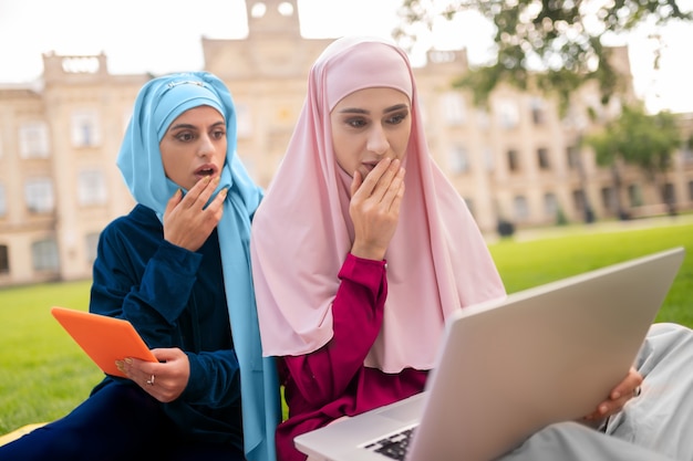 Studiare prima delle lezioni. Studenti musulmani internazionali che studiano insieme prima delle lezioni seduti sull'erba