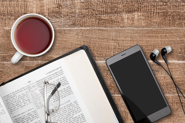 Studio biblico con smartphone e caffè, script sfocato