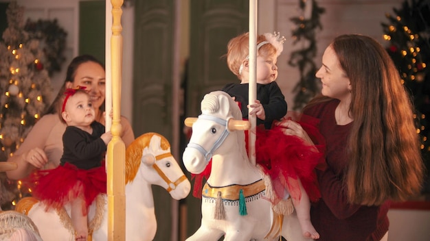 Studio decorato di Natale due bambini con le loro madri sorridenti sedute sulla giostra