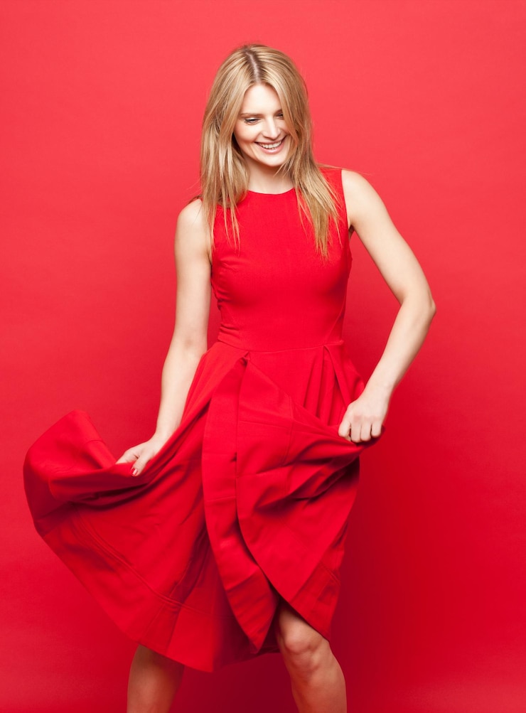 Foto studio di moda e abbigliamento della donna con danza per vincere il successo e la fiducia femminile persona femminile felice e sorridente con celebrazione per il glamour libertà e stile chic su sfondo rosso