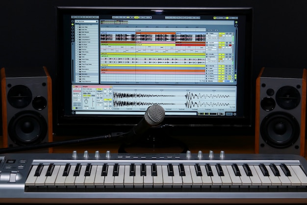 Studio di registrazione domestico. Tastiera sullo schermo, altoparlanti e microfono.
