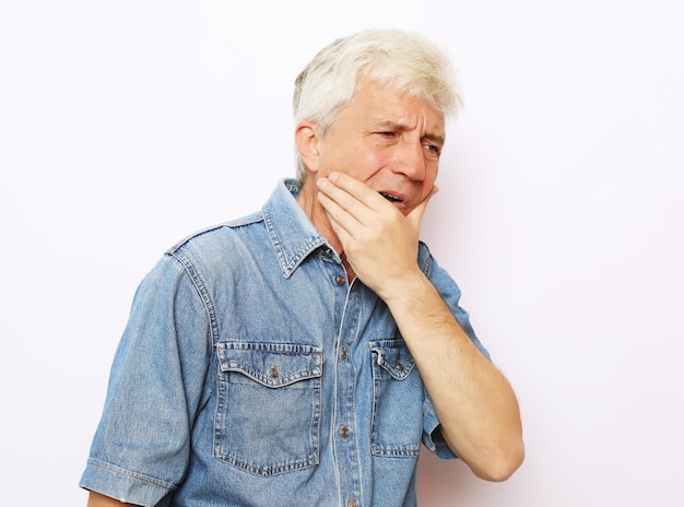 Studio di un uomo anziano infelice che preme la guancia cercando di lenire il mal di denti