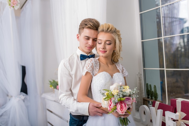 Studio fotografico di matrimonio con baci e abbracci. Coppia felice. Gli amanti della sposa e dello sposo nella decorazione di lusso.