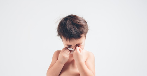 Studio immagine di un bambino con fazzoletto. Il bambino malato isolato ha naso che cola.