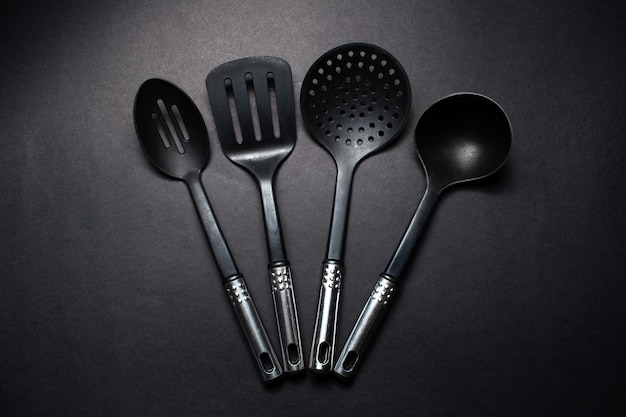 Studio immagine di utensili da cucina in plastica nera con maniglie cromate.