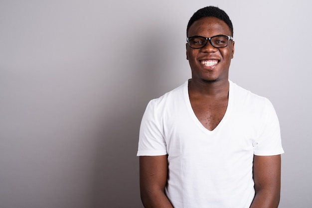 Studio shot del giovane africano che indossa una camicia bianca e occhiali da vista su sfondo bianco