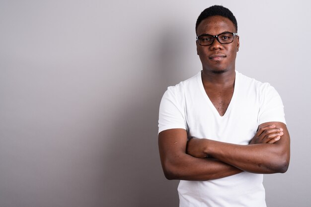 Studio shot del giovane africano che indossa una camicia bianca e occhiali da vista su sfondo bianco