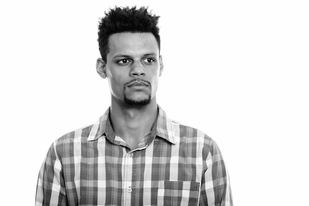 Studio shot del giovane barbuto imprenditore africano con capelli afro isolata contro uno sfondo bianco in bianco e nero