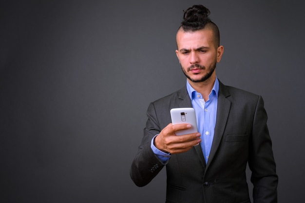 Studio shot di bel imprenditore turco utilizzando il telefono cellulare su uno sfondo grigio