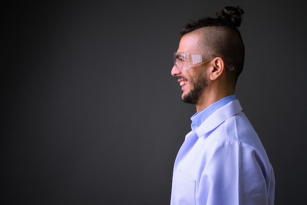 Studio shot di bel uomo turco medico indossando occhiali protettivi contro uno sfondo grigio