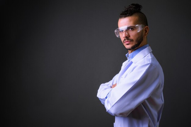 Studio shot di bel uomo turco medico indossando occhiali protettivi contro uno sfondo grigio