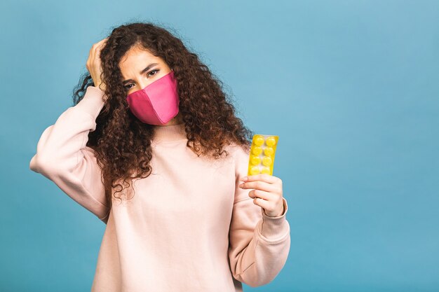 Studio shot di donna infetta con pillole in mano, signora che indossa la maschera protettiva, impedisce la diffusione di virus pericolosi