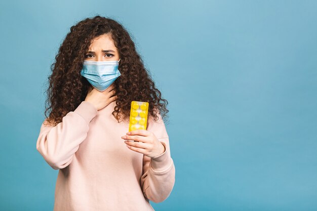 Studio shot di donna infetta con pillole in mano, signora che indossa la maschera protettiva