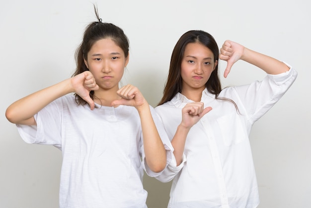 Studio shot di due giovani belle donne coreane come amici insieme su sfondo bianco