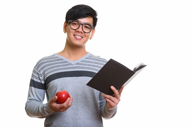 Studio shot di felice uomo asiatico sorridente azienda libro e rosso appl