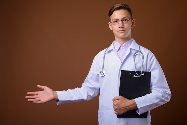 Studio shot di giovane bel medico su sfondo marrone