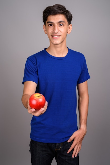 Studio shot di giovane bel ragazzo adolescente persiano su sfondo grigio