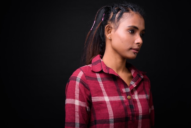 Studio shot di giovane bella donna asiatica hipster con capelli intrecciati su sfondo nero