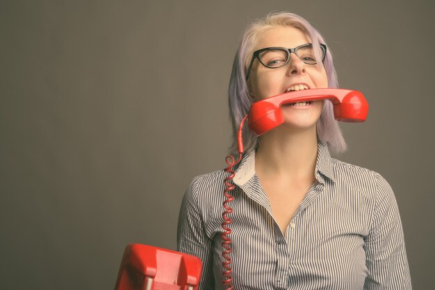 Studio shot di giovane bella imprenditrice con corti capelli colorati su grigio