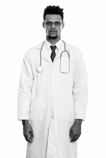 Studio shot di giovane bello barbuto medico africano uomo isolato su sfondo bianco in bianco e nero