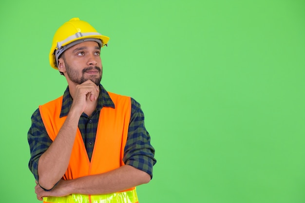 Studio shot di giovane bello barbuto operaio edile uomo persiano contro la chiave di crominanza con sfondo verde