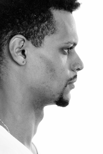 Studio shot di giovane bello barbuto uomo africano con capelli afro isolata contro uno sfondo bianco in bianco e nero