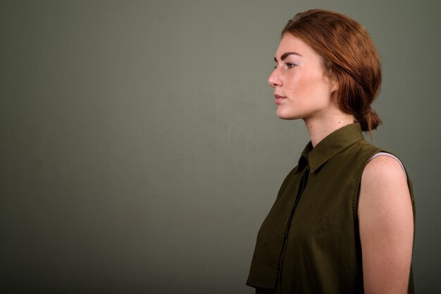 Studio shot di giovane donna che indossa top senza maniche verde su sfondo colorato