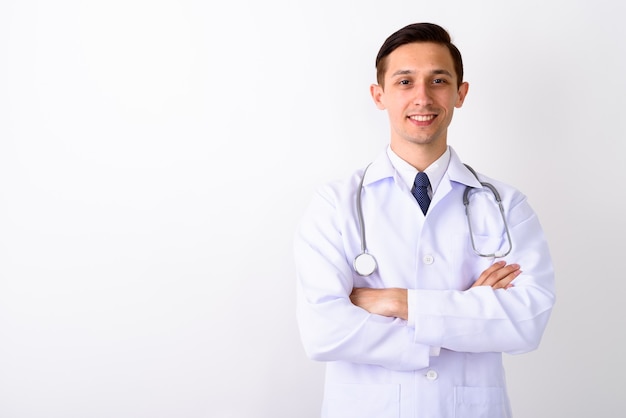 Studio shot di giovane medico uomo felice sorridente con le braccia incrociate