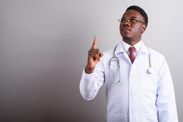 Studio shot di giovane uomo africano medico indossando occhiali da vista su sfondo bianco