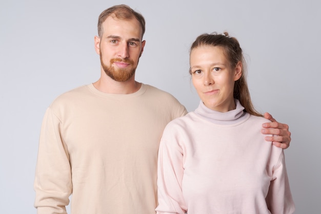 Studio shot di giovane uomo barbuto e giovane bella donna insieme contro il bianco