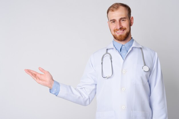 Studio shot di giovane uomo barbuto medico contro bianco