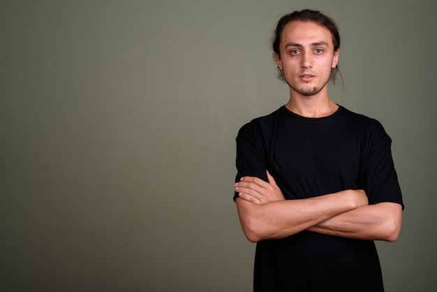 Studio shot di giovane uomo bello che indossa la camicia nera su sfondo colorato