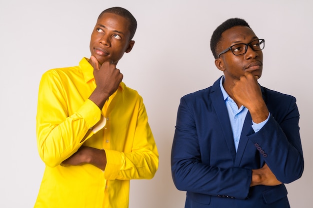 Studio shot di giovane uomo d'affari africano calvo e giovane uomo d'affari africano insieme su sfondo bianco