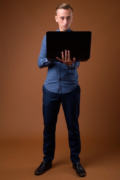 Studio shot di giovane uomo d'affari bello contro marrone