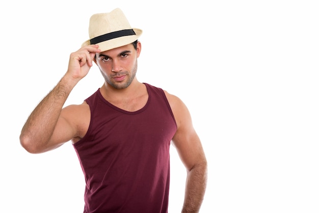 Studio shot di giovane uomo ispanico bello tenendo il cappello sulla testa