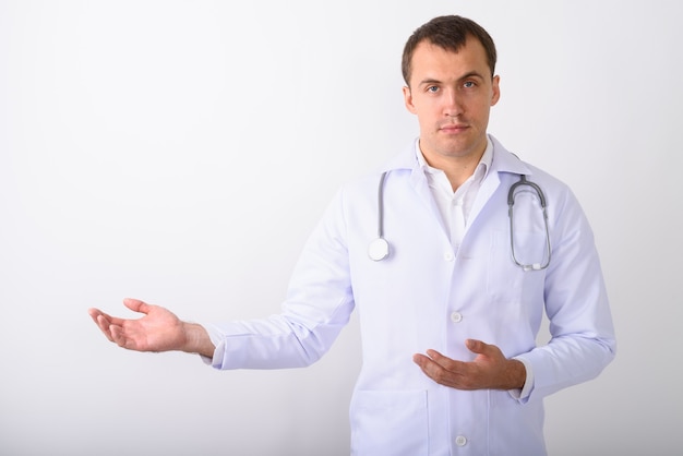 Studio shot di giovane uomo muscoloso medico che mostra qualcosa di nuovo