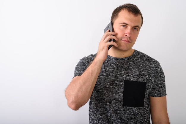 Studio shot di giovane uomo muscoloso parlando al telefono cellulare contro