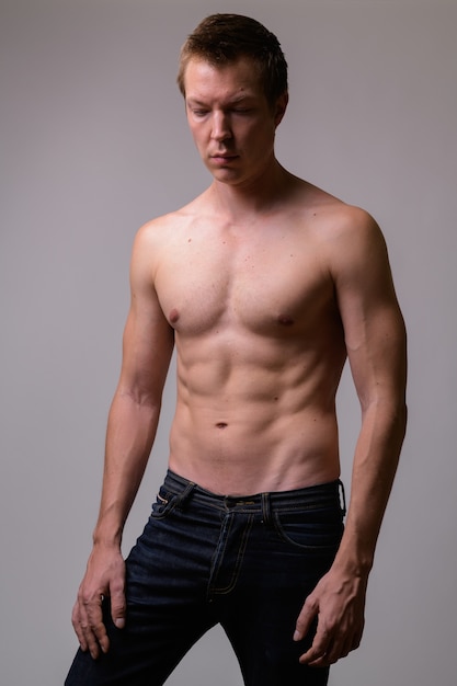 Studio shot di giovane uomo torso nudo muscolare bello su sfondo bianco