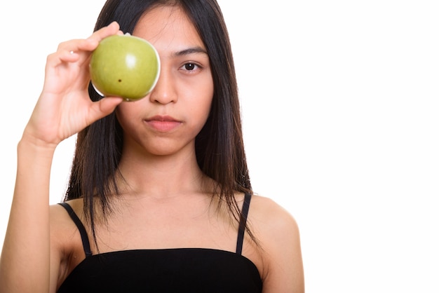 Studio shot di giovani asiatici ragazza adolescente che copre gli occhi con mela verde