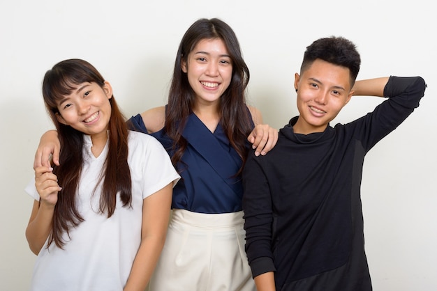 Studio shot di tre giovani belle donne asiatiche come amici insieme su sfondo bianco