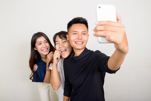 Studio shot di tre giovani belle donne asiatiche come amici insieme su sfondo bianco