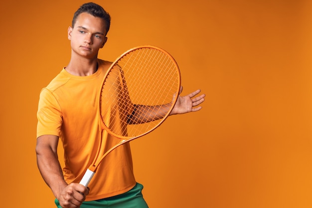 Studio shot di un giovane giocatore di tennis in possesso di racchetta