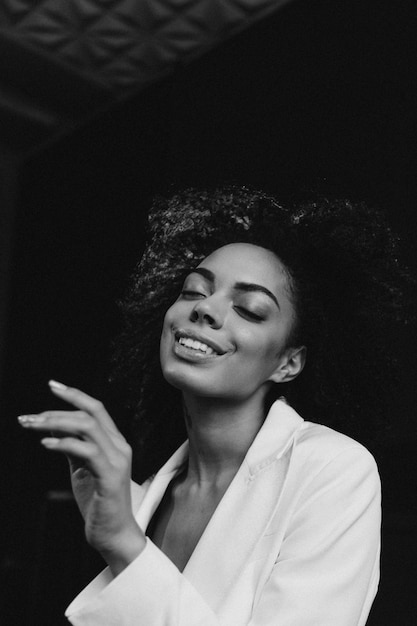 Studio shot di un modello femminile dalla pelle scura felicissimo che ride felicemente e posa vicino ai fiori