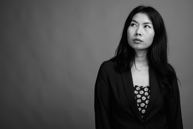 Studio shot di una donna asiatica che indossa un abito e un maglione cardigan su sfondo grigio in bianco e nero