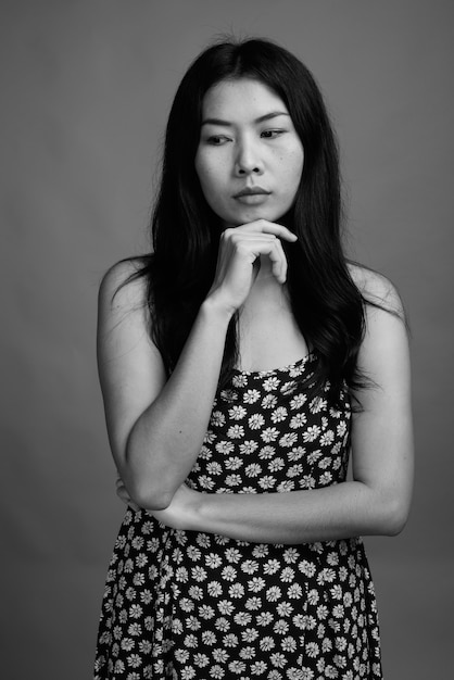 Studio shot di una donna asiatica che indossa un abito su sfondo grigio in bianco e nero