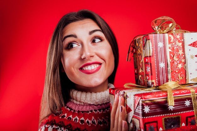 Studio shot di una giovane donna con un maglione islandese che tiene scatole regalo regali di Natale o Capodanno