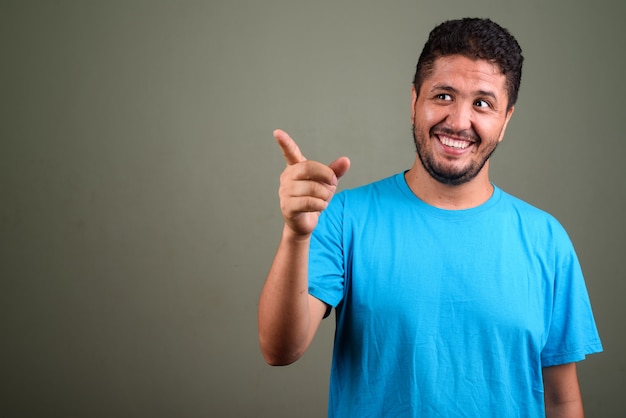 Studio shot di uomo barbuto che indossa la maglietta blu contro colorato