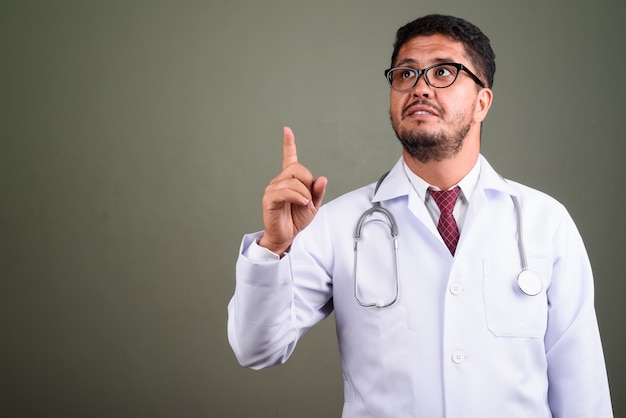 Studio shot di uomo barbuto medico contro colorato