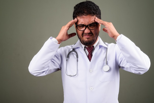 Studio shot di uomo barbuto medico contro colorato